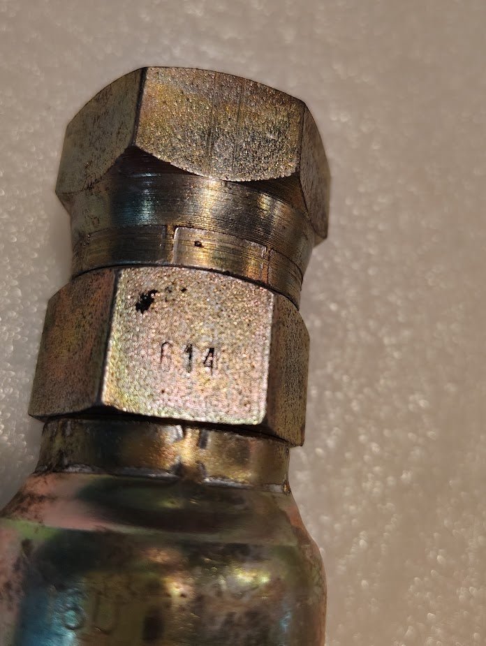 A close-up view of a Weatherhead 16U-614 (1 Hose x 7/8 JIC Female Fitting, CS09-16X14), compatible with the 100R series, shows visible scratches, discoloration, and 14 stamped on its metallic hexagonal surface.
