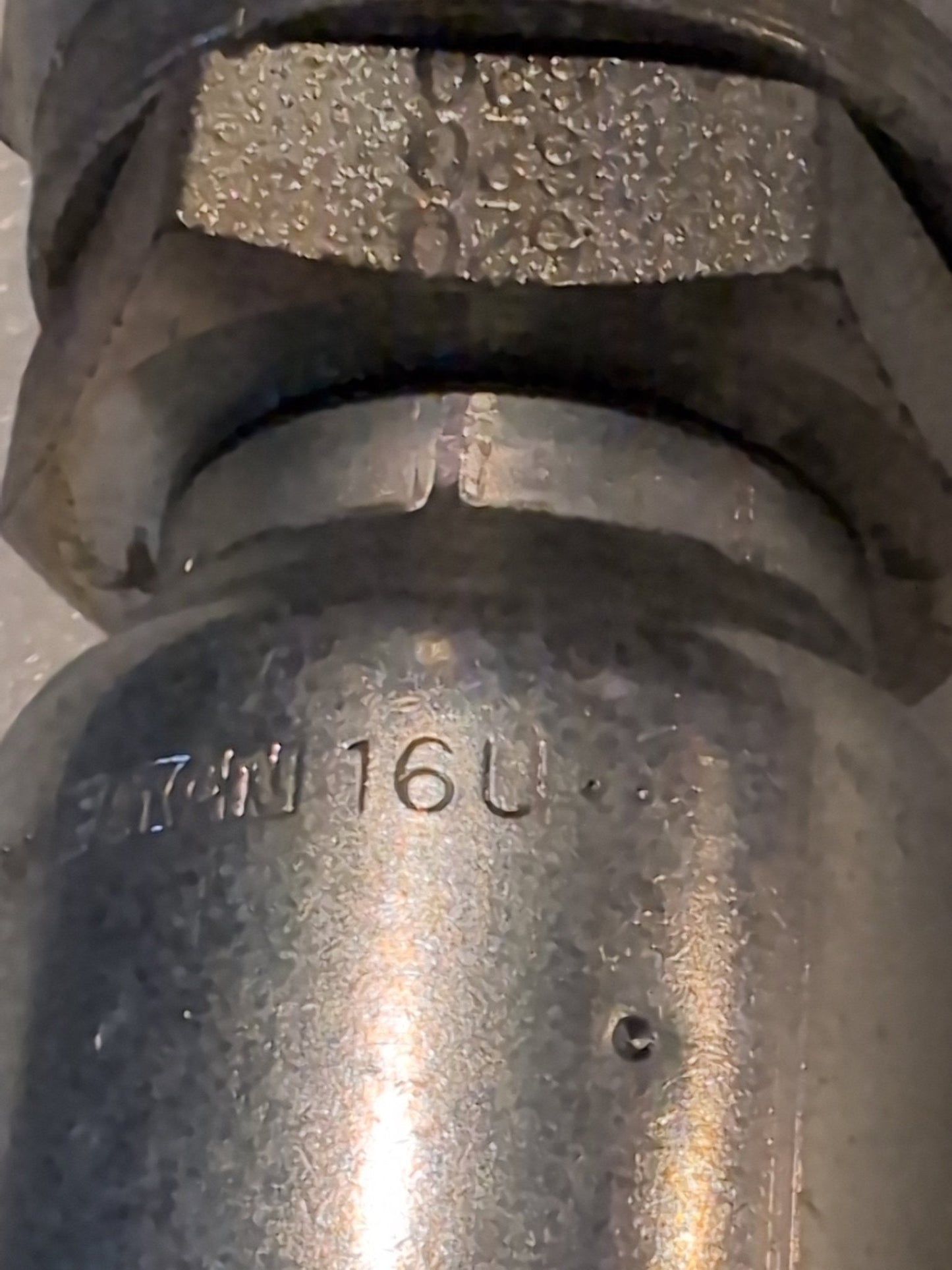 Close-up of a Weatherhead 16U-620 (CS09-16X20) pipe fitting, a 1 hose x 1 1/4 JIC female fitting. The metal surface has engraved 16U, with visible texture and tooling marks, typical of hydraulic hardware.