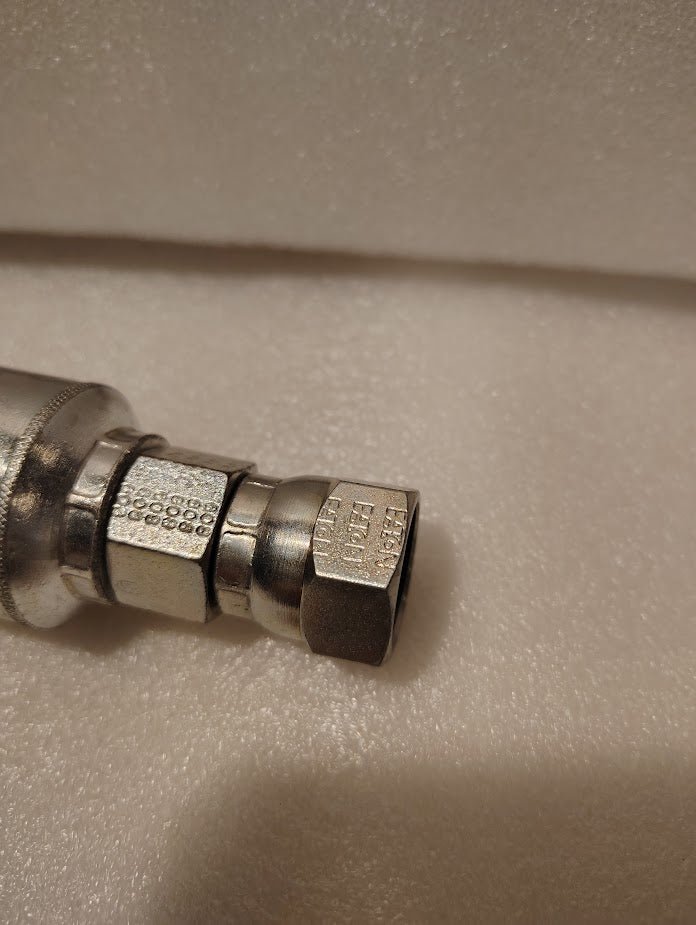 Close-up of a Weatherhead 43008U-608 1/2 Hose x 1/2 JIC Female Fitting (GW09-8x8) with hexagonal nut, visible threading, and stamped markings against a soft white textured background.