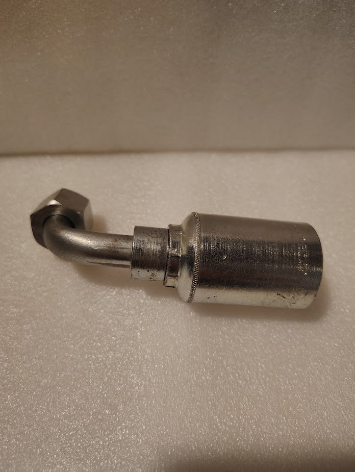 A close-up of the 43008U-668, a metallic fitting with a bent tube and hex nut, resting on a textured white surface.