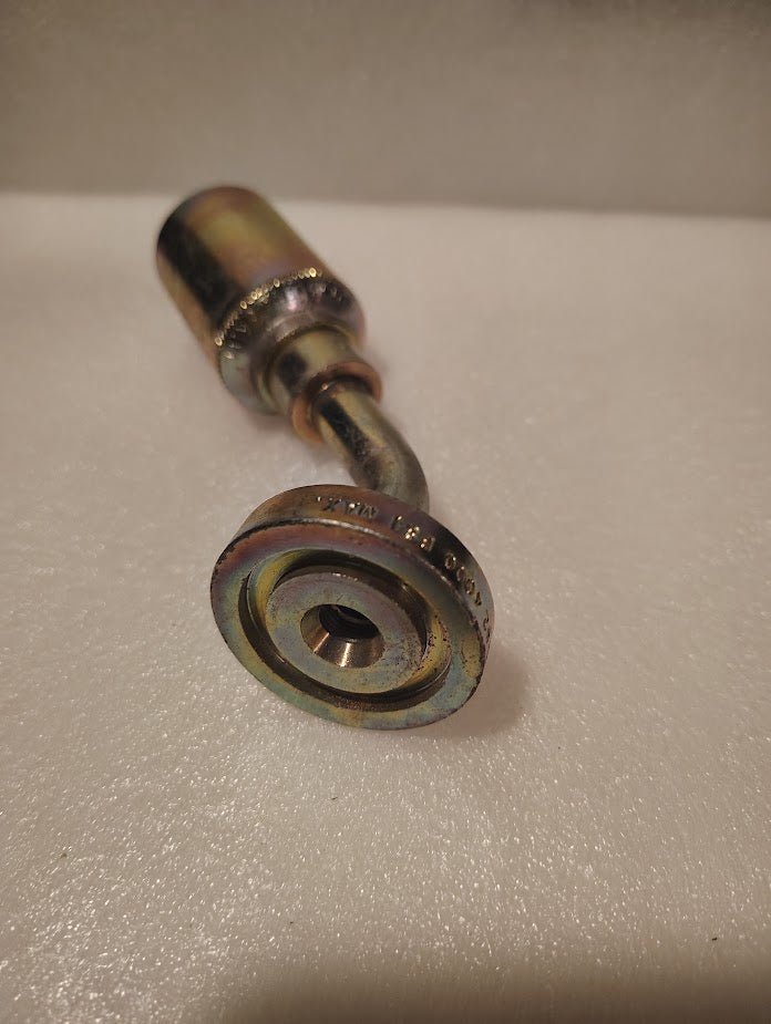 A close-up view of the 43008U-D42 | 1/2 Hose x 3/4 Code 62 Flange Fitting - 45 bend (GW61-08x12), a metallic, cylindrical part with a bent shaft and engraved markings, resting on a textured white surface.
