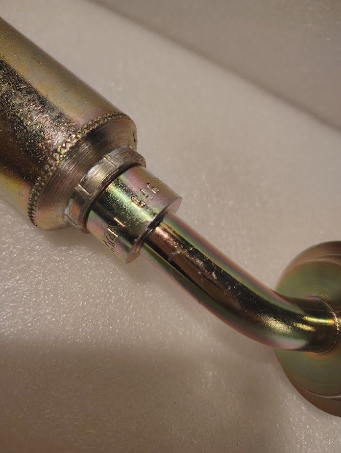 Close-up of a 43008U-G46 GW50-8x16 fitting with a 1/2 hose x 1 Code 61 flange, featuring a 45° bend. The threaded, stamped metallic piece has a shiny, iridescent finish and rests on a white surface. Ideal for hydraulic hoses.