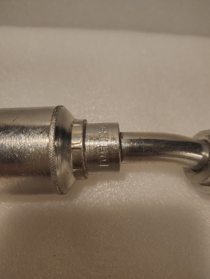 Close-up photo of a 43008U-H01 | 1/2 Hose x 1/2 Code 61 Flange Fitting - 22.5 bend (GW48-8x8) with shiny metal surface, engravings such as PAT. PEND., resting on a soft white background.