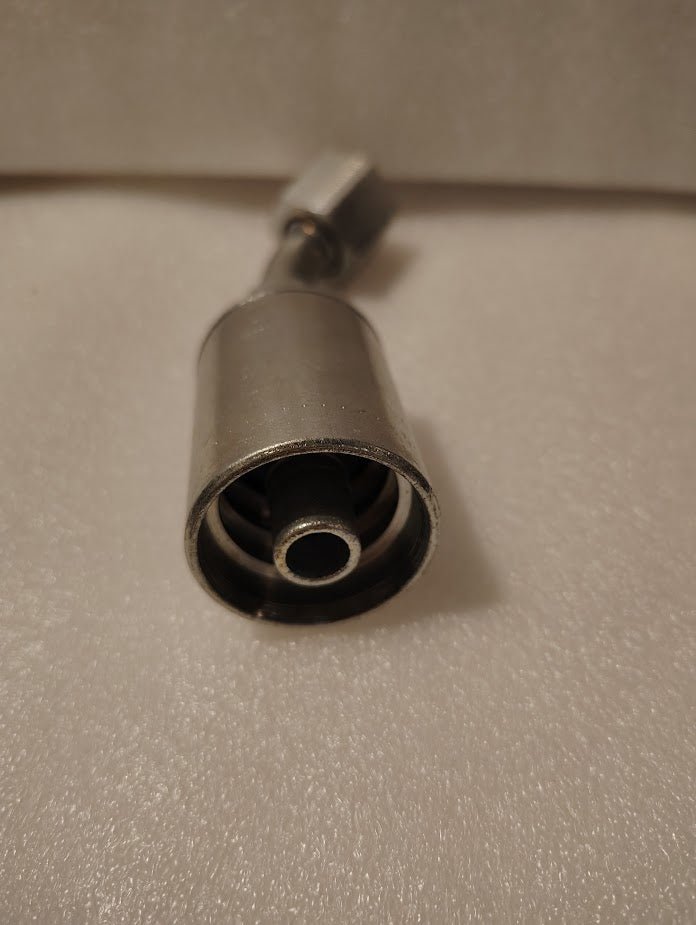 Close-up of a metal cylindrical 43008U-L68 Weatherhead 1/2 Hose x 1/2 ORFS Female Fitting (GW31-8x8) with central tube and concentric rings, placed on a textured white surface; background is blurred.