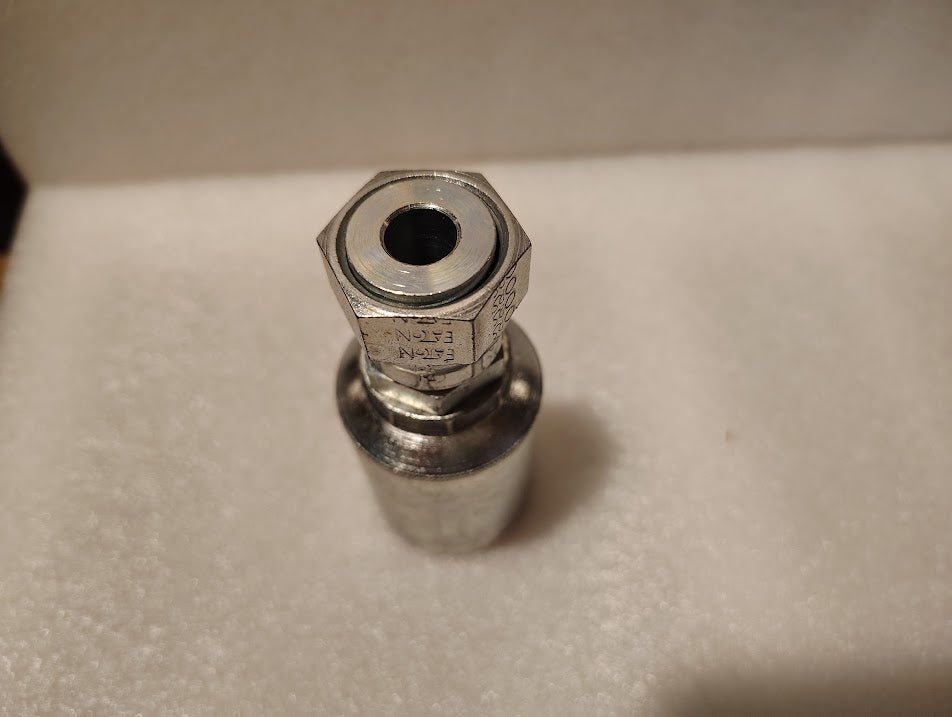 A close-up of the Weatherhead 43008U-S68 1/2 Hose x 1/2 ORFS Female Fitting (GW30-8x8) featuring a threaded hole, shown upright on a soft, white, textured surface.