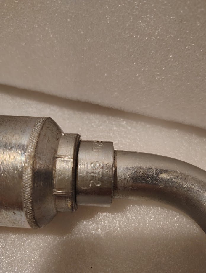 Close-up of a metallic pipe with Weatherhead 43012U-672 (3/4 Hose x 3/4 JIC Female Fitting, GW26-12x12) and engraved markings, resting against a white textured background—ideal for compatible hoses and hydraulic applications.