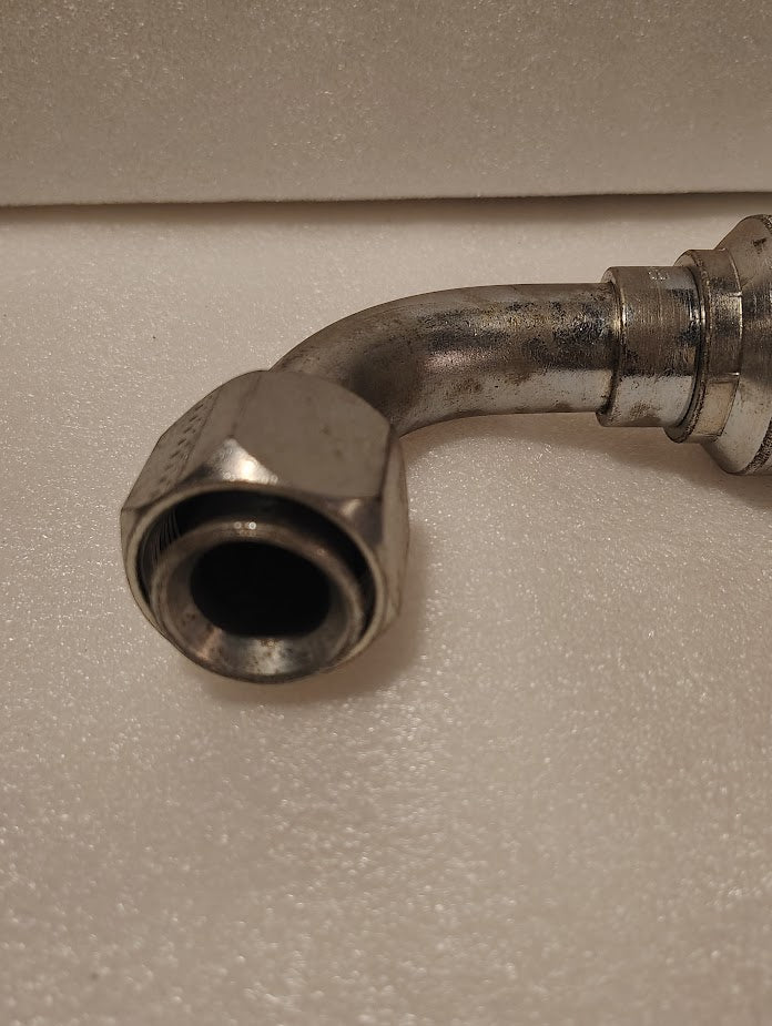 A 43016U-676 | 1 Hose x 1 JIC/SAE Swivel Fitting - 90 bend (GW26-16x16) with hexagonal nut and curved elbow, featuring a female swivel, is shown against a white textured background.