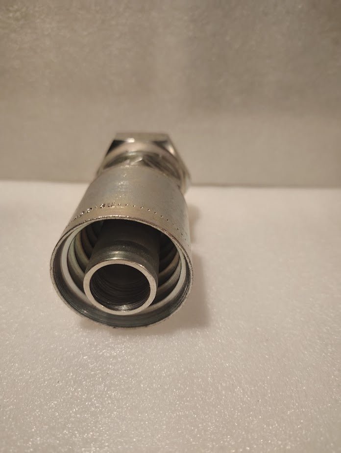 Close-up of a 43016U-80C | 1 Hose x M42x2.0 DIN Heavy (Metric S) Straight Swivel Fitting, showing its ridged interior and threaded section on a white textured surface with a blurred background.