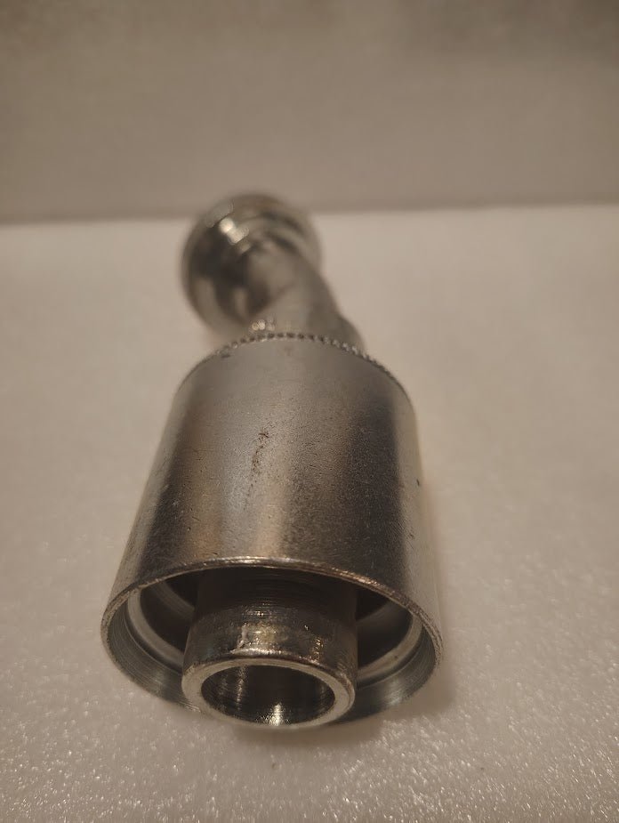 Close-up of a 43016U-H23 | 1 Hose x 1 Code 61 Flange Fitting - 30 bend (GW49-16x16) lying on a textured white surface, precision-crafted with its threaded end facing the camera for easy pipe attachment.