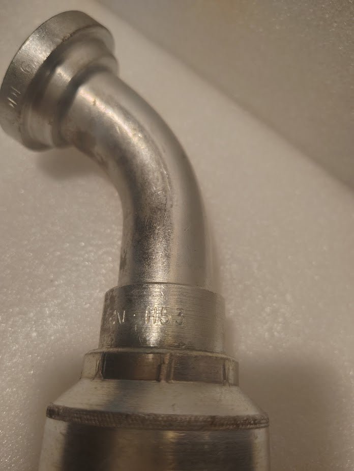 A close-up of a metallic 43016U-H53 | 1 Hose x 1 Code 61 Flange Fitting - 60 bend (GW51-16x16), featuring engraved numbers and letters, set against a textured white background.