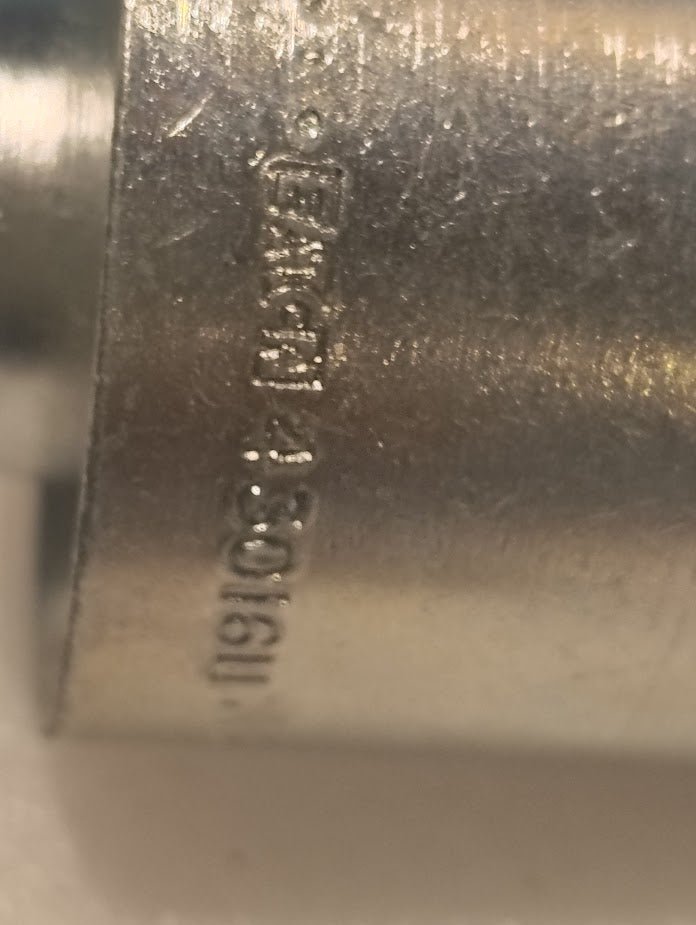A close-up image of a metallic 43016U-H53 | 1 Hose x 1 Code 61 Flange Fitting - 60 bend (GW51-16x16) with engraved text and numbers on its shiny surface, showing branding and specifications.