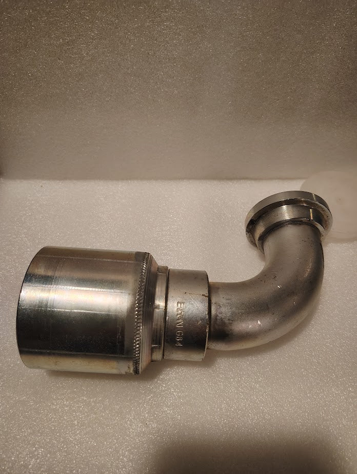 A 43024U-G84 | 1 1/2 Hose x 1 1/2 Code 61 Flange Fitting with a 90° bend (GW53-24x24), similar to hydraulic hose fittings, is shown on a white textured surface.