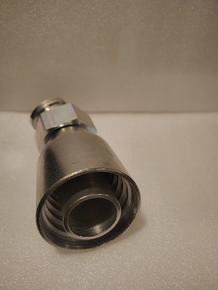 A close-up photo of a 43024U-L84 | 1 1/2 Hose x 1 1/2 ORFS Swivel Fitting - 45 bend (GW31-24x24), highlighting its hex nut and ribbed end, set on a white textured surface.