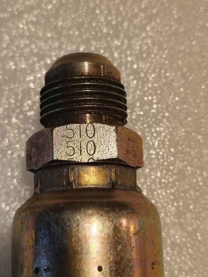 Close-up of a 12U-510 Weatherhead fitting, featuring a threaded top and hexagonal nut marked 510, compatible with 100R series hydraulic hoses, on a textured light surface.