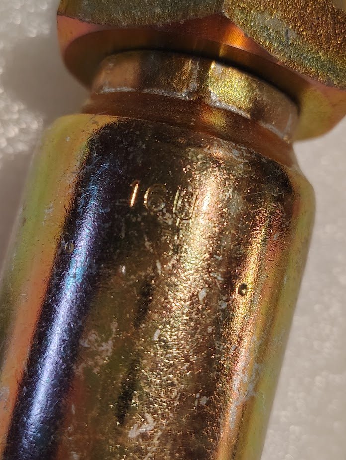 Close-up of a shiny metallic pipe with a hexagonal nut, similar to the Weatherhead 16U-520 1 Hose x 1 1/4 JIC Male Fitting - Straight Solid. The surface shows wear and slight discoloration, with 1GU engraved, suggesting its past use in hydraulic hose fittings.