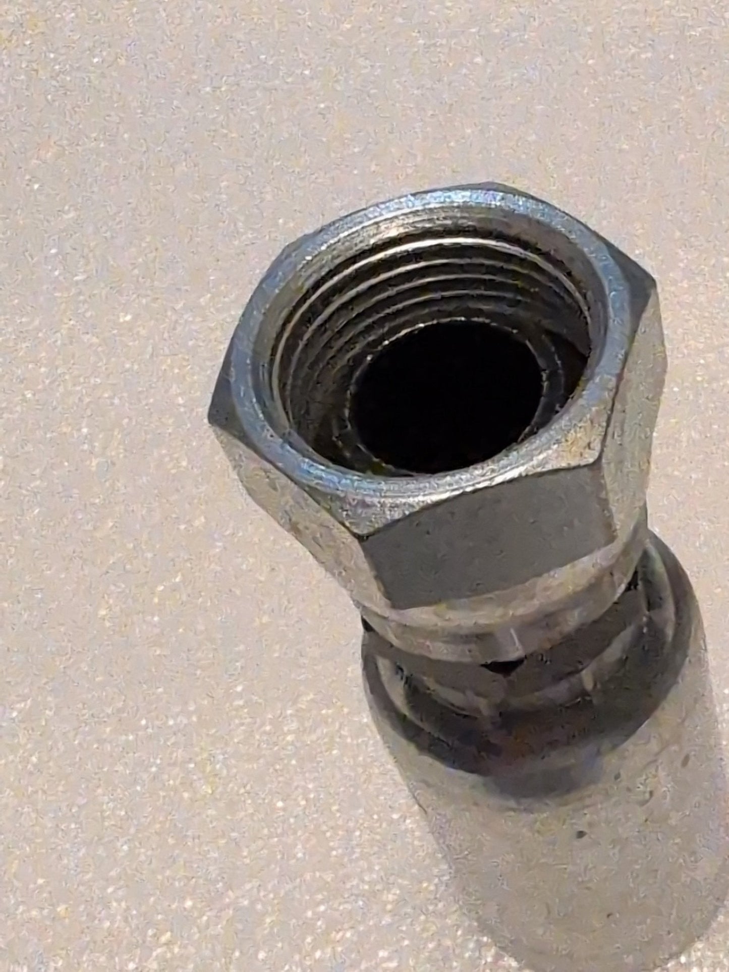 A 12U-362 Weatherhead connector, a metallic 3/4 Hose x 3/4 BSPP Female Fitting with a hex nut, is angled on a light-textured surface. The shiny swivel connector shows visible internal threading, ideal for hydraulic hose applications.