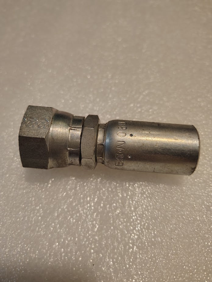 The 06U-358 Weatherhead fitting, featuring a hex nut and cylindrical connector, is designed for compatibility with various hydraulic hoses. Its body has engraved markings and rests on a textured surface.