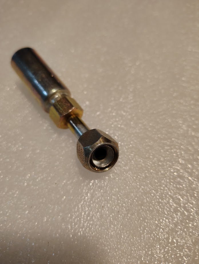 A Weatherhead 04U-685 1/4 Hose x 5/16 JIC/SAE Female Fitting with a 45 swivel, featuring a threaded end and hexagonal nut, rests on a textured white surface, reflecting light and showcasing versatility for various hydraulic hose needs.