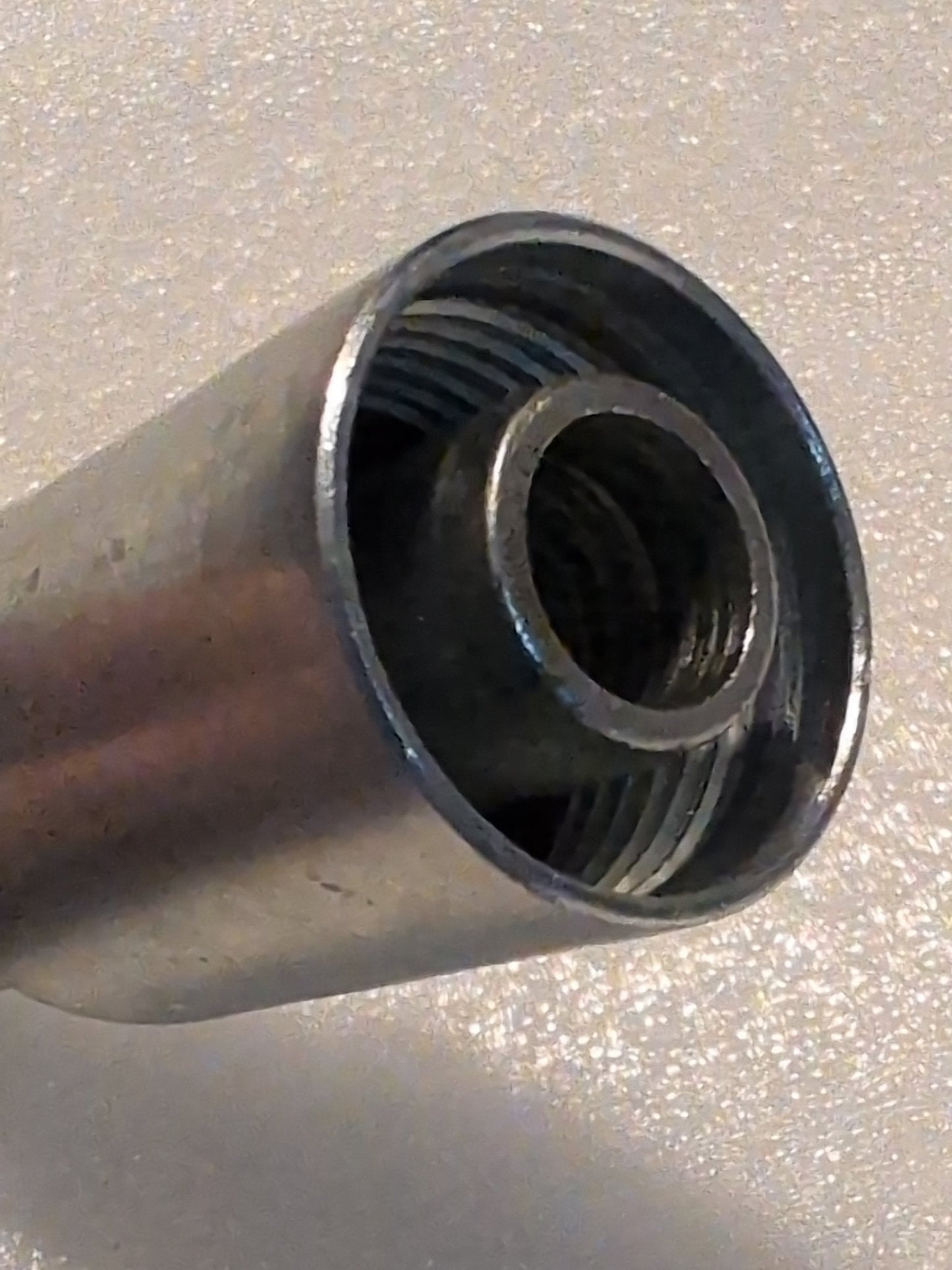 A close-up of a 12U-670 Weatherhead fitting showcases its threaded interior and textured surface. The focus is on the open end, highlighting the concentric rings and metallic sheen, similar to precision-engineered Weatherhead 3/4 Hose x 5/8 JIC/SAE Female Fitting - 90 Swivel.