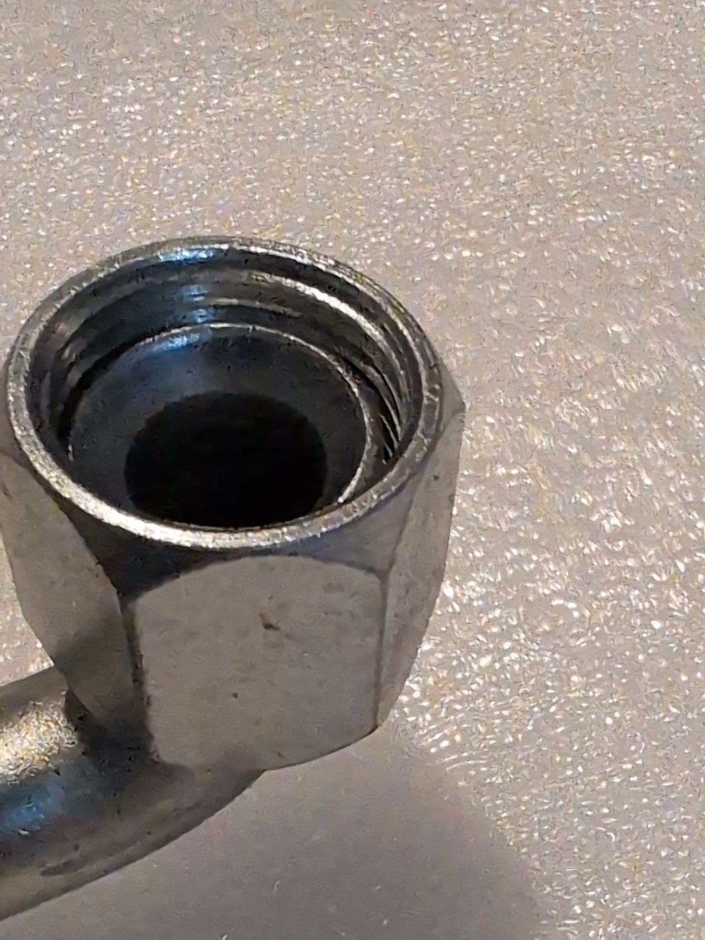 A close-up of the Weatherhead 12U-670, a 3/4 hose x 5/8 JIC/SAE female fitting with a 90-degree swivel, shows the metal hexagonal nuts inside threads against a textured, light backdrop.
