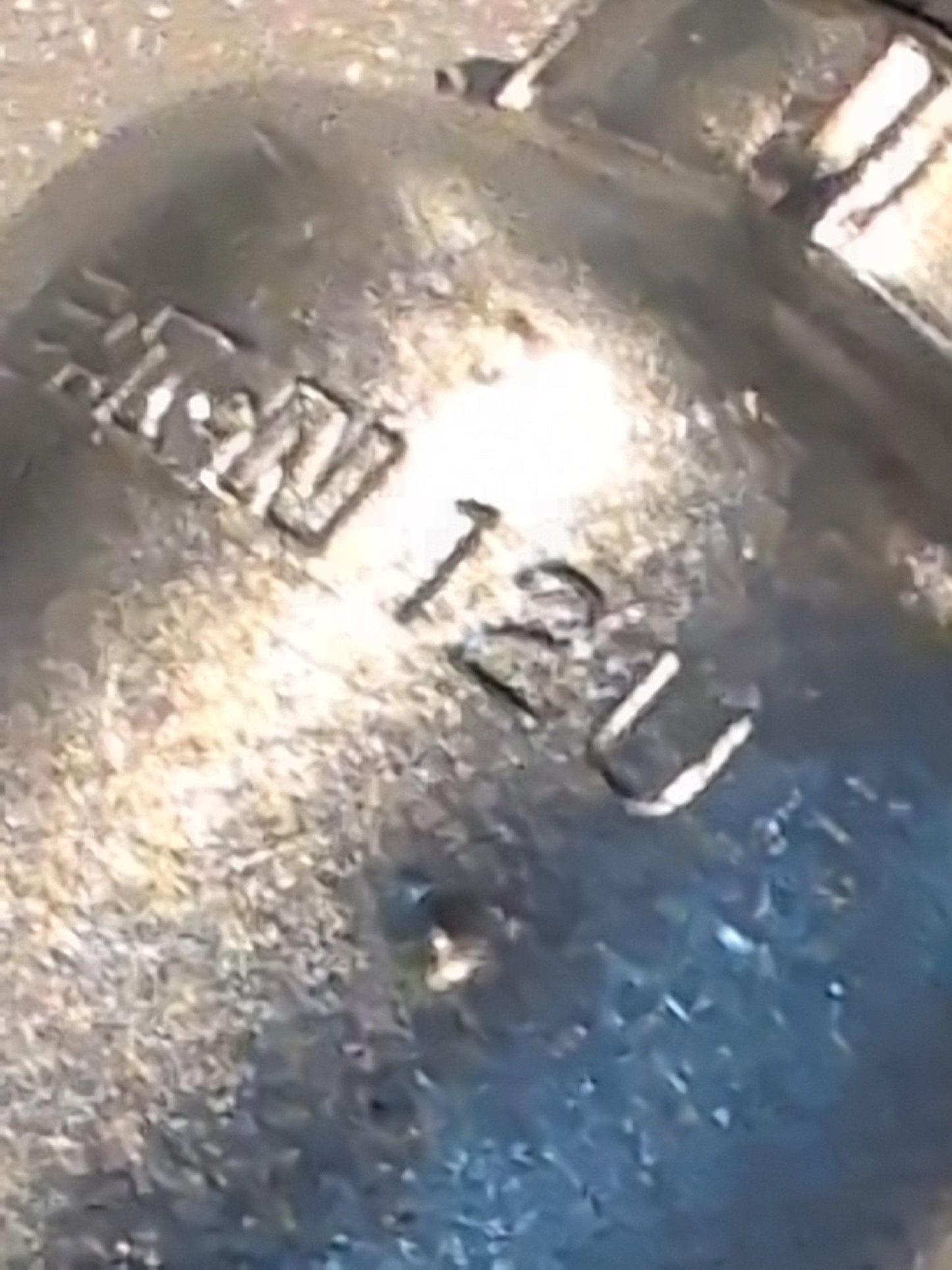 Close-up of a metallic object with RN 120 engraved, resembling the shiny, textured finish of the 12U-670 Weatherhead 3/4 Hose x 5/8 JIC/SAE Female Fitting - 90 Swivel, beautifully reflecting light across its surface.