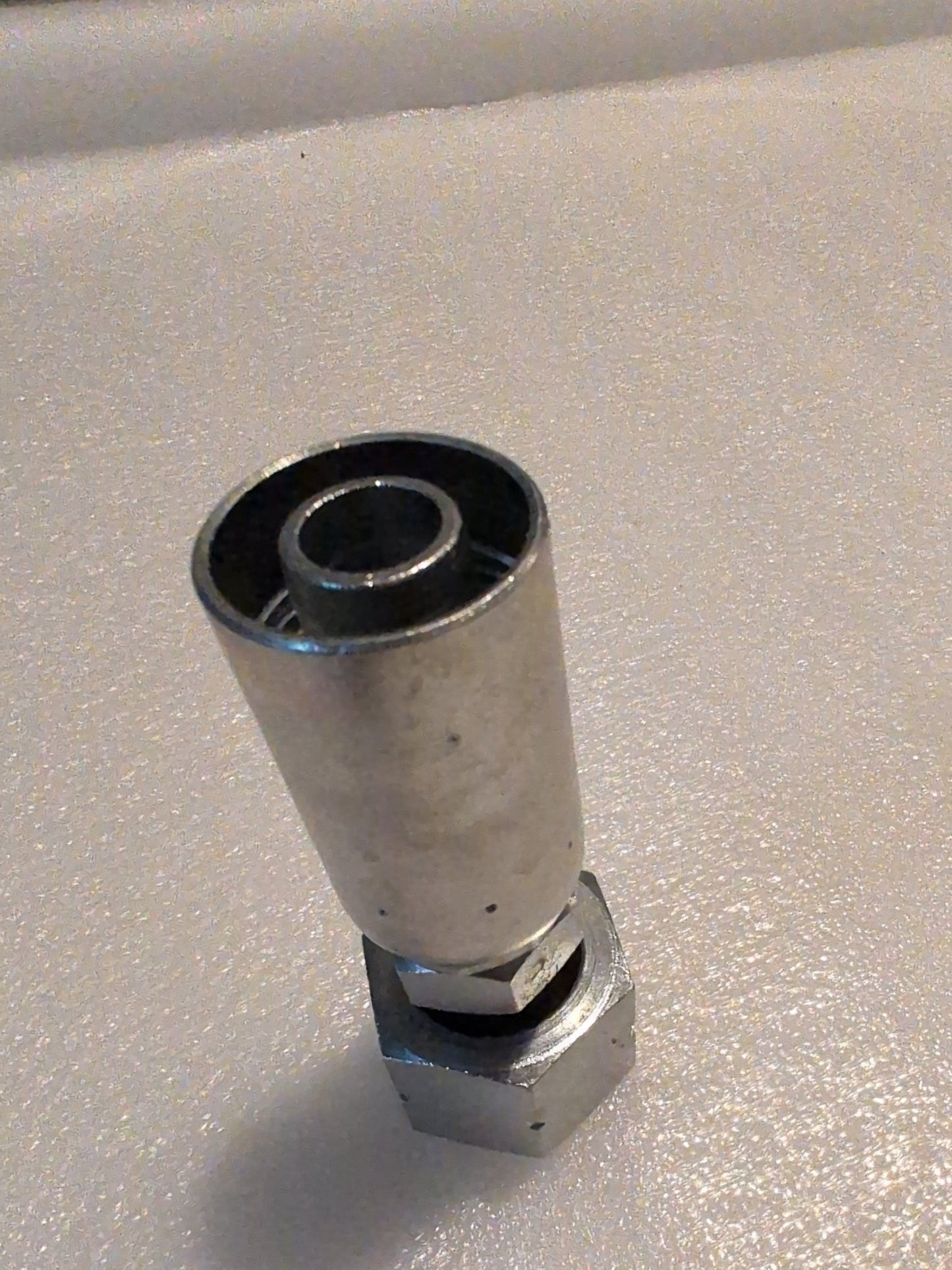 Close-up of a Weatherhead 10U-S72 metal socket adapter, featuring a hexagonal base and a circular opening at the top, on a textured light surface.