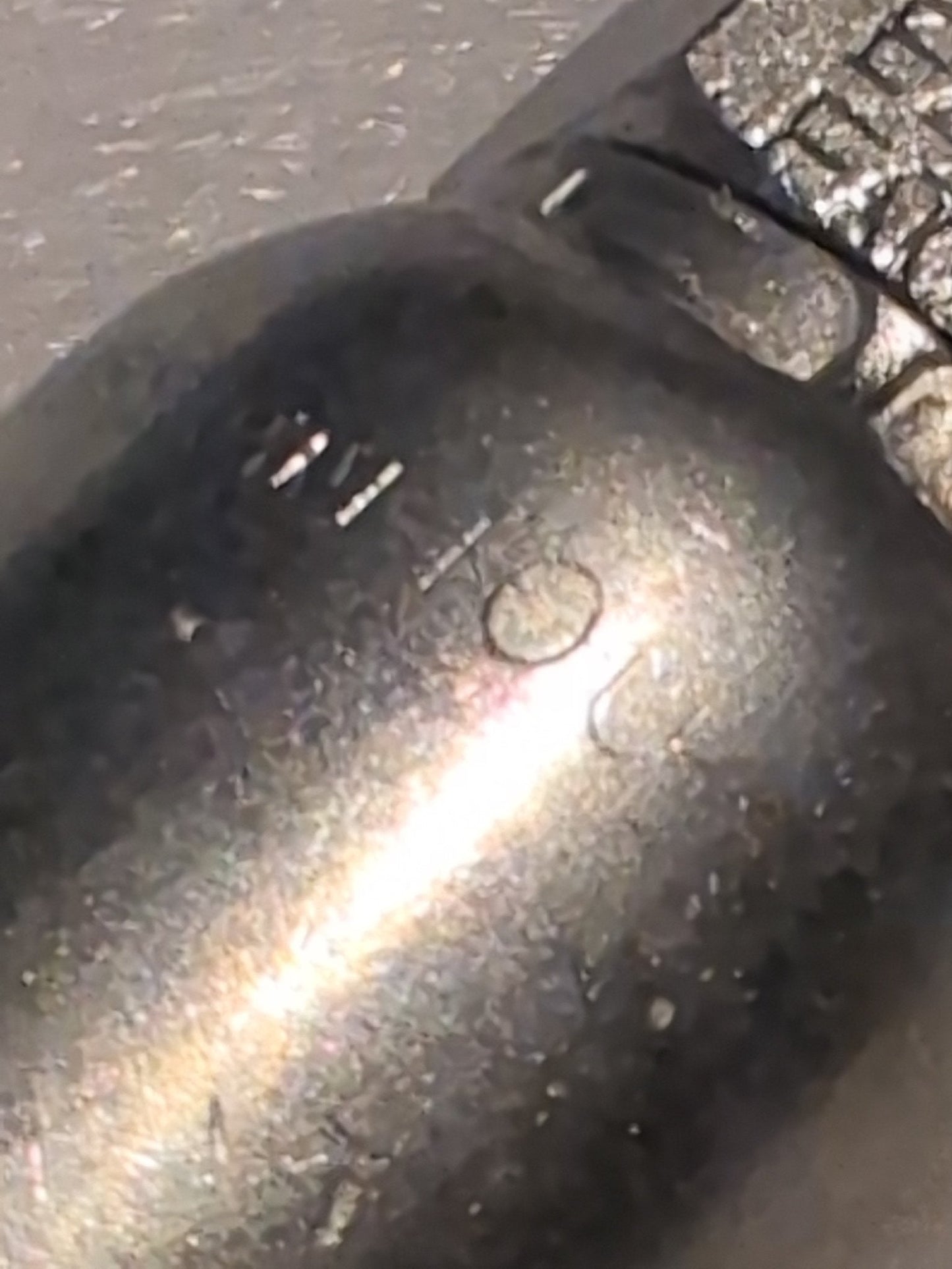 A close-up of the Weatherhead 10U-S72 fitting reveals a textured, slightly worn metal surface with a circular indentation. It reflects light, creating a shiny appearance and casting gentle shadows.