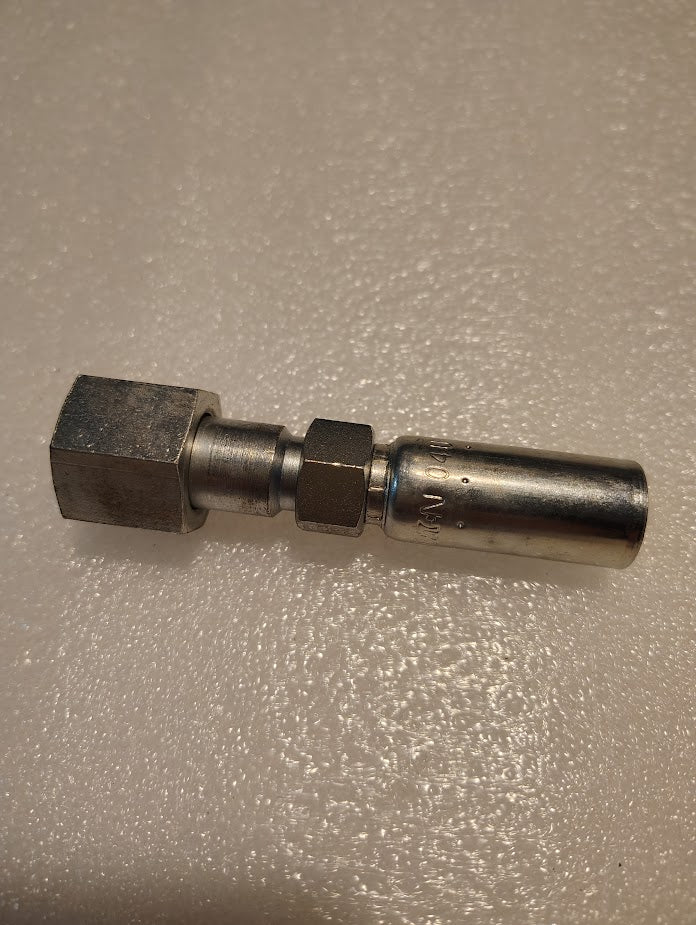 The Weatherhead 04U-S68, a metal coupling connector, sits on a textured beige surface, featuring a hexagonal and cylindrical end joined by a middle section. This metallic and shiny tool evokes an industrial look akin to hydraulic hose fittings.