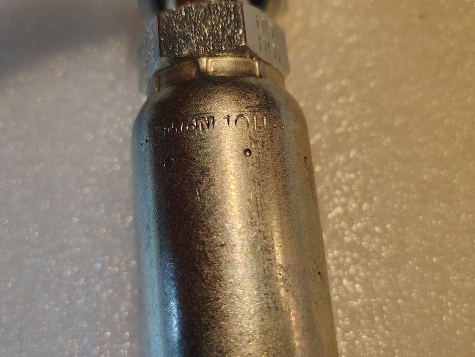 Close-up of a metallic 10U-L70 Weatherhead 5/8 Hose x 5/8 ORF Female Fitting - 45 Swivel with a threaded end. The surface is slightly worn, with engraved text partially visible, suggesting its use in hydraulic hose applications.