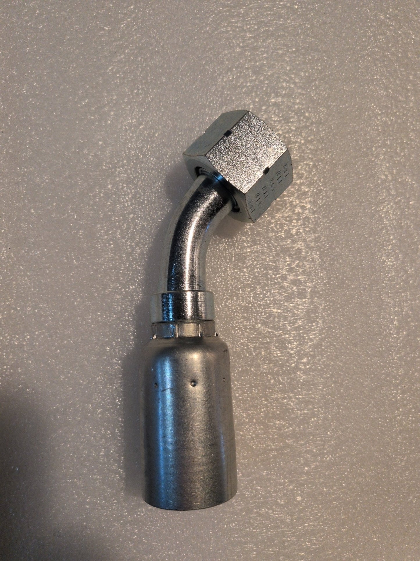 The 12U-L72 Weatherhead fitting, a 3/4 hose with a 45-degree swivel and hexagonal connector, lies gracefully on a textured white surface.