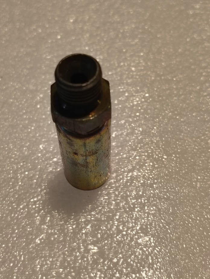 A Weatherhead 04U-P54 fitting, a 1/4 hose x 1/4 BSPT male straight solid connector, stands upright on a textured, reflective surface, displaying signs of wear and discoloration.