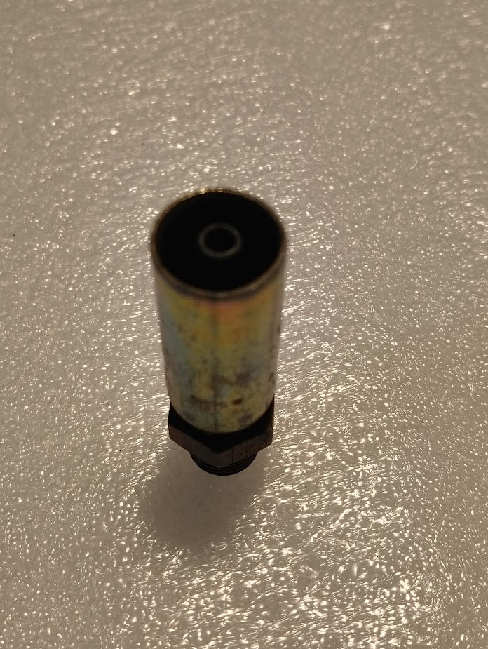 A single metal spray paint nozzle sits upright on a textured white surface, echoing the design of the 04U-P54 Weatherhead 1/4 Hose x 1/4 BSPT Male Fitting - Straight Solid. The nozzle is slightly worn, showing paint residue and a metallic shine under light.