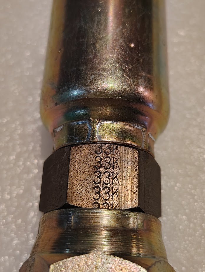 Close-up of a Weatherhead 16U-33K fitting engraved with 38A on the hexagonal part, featuring a shiny, reflective surface against a textured white background.