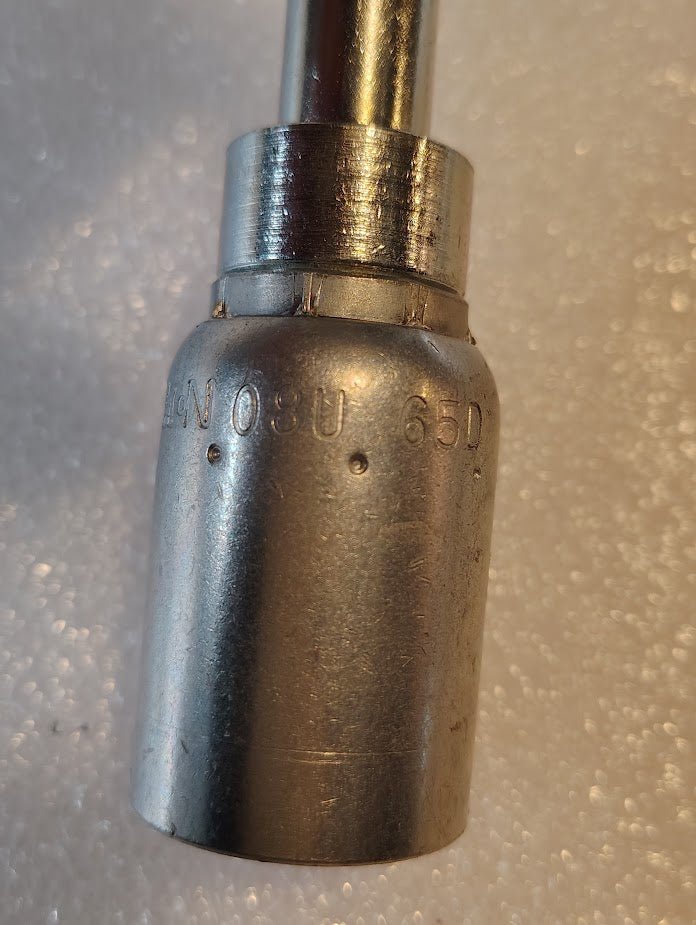 Close-up of a Weatherhead 1/2 Hose x M22x1.5 DIN Female Fitting - 90 Swivel with engraved codes 08U and 65D, compatible with interchangeable fittings, positioned upright against a textured, white background.