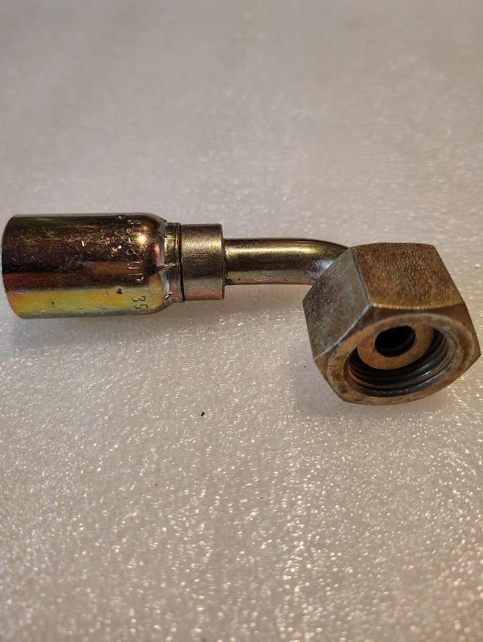 The 08U-80P Weatherhead fitting, compatible with 100R hoses, features a hexagonal nut and cylindrical connector. It has a slightly bent design and rests on a textured white surface.