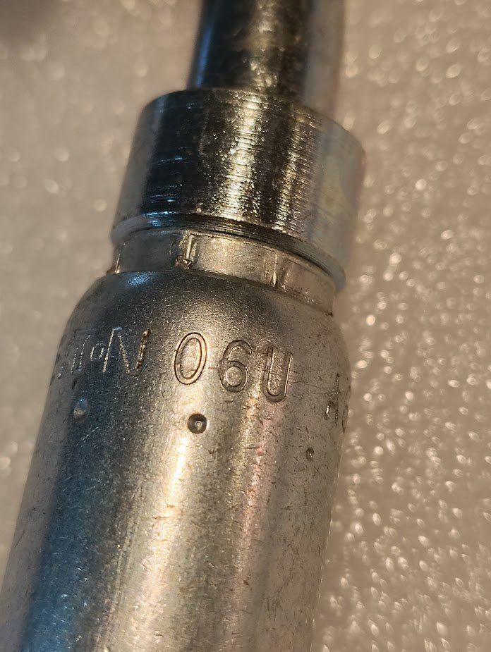 A close-up of the Weatherhead 06U-A68 CS33-6X8 3/8 Hose x 1/2 ORF Female Fitting, showing engraved markings against a textured foam background—typically used for hydraulic hose assembly.