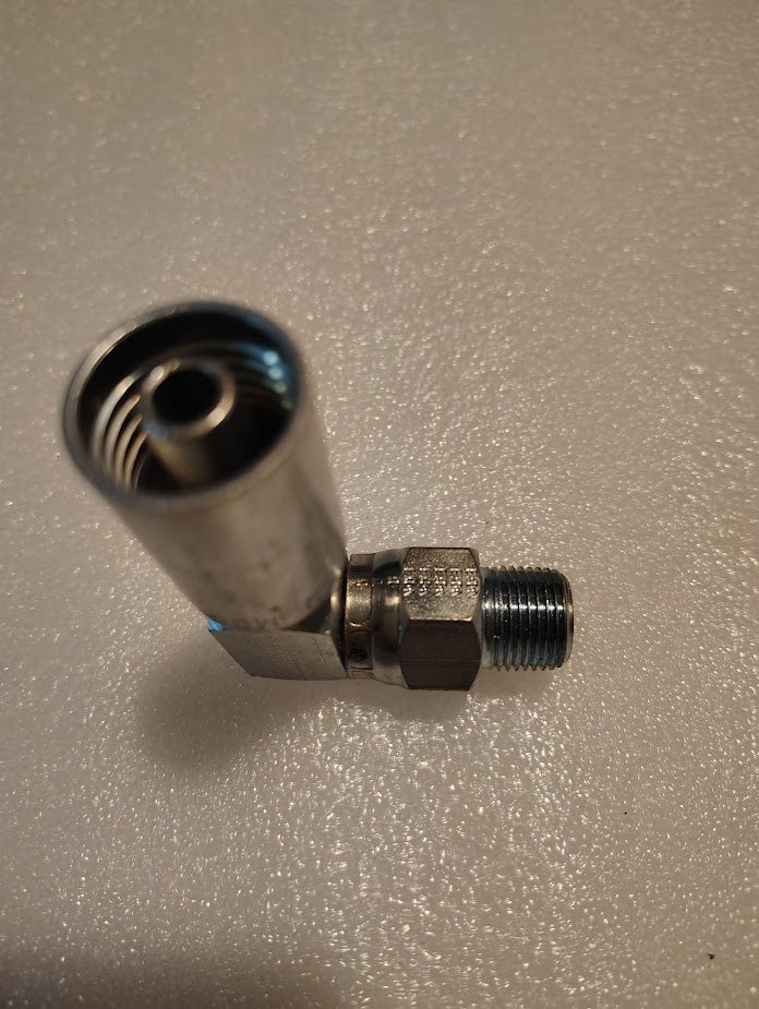 A close-up of a Weatherhead 06U-M06 fitting (3/8 hose x 3/8 NPTF male, CS14-6X6) with threaded ends, lying on a textured, light-colored surface. This L-shaped metal part is commonly used in hydraulic applications.