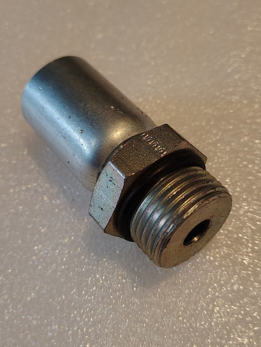 The 08U-P12 Weatherhead 1/2 Hose x 3/4 ORB Male Fitting - Straight Solid, a metallic cylindrical piece with a threaded end, is positioned at an angle on a textured, light-colored surface.