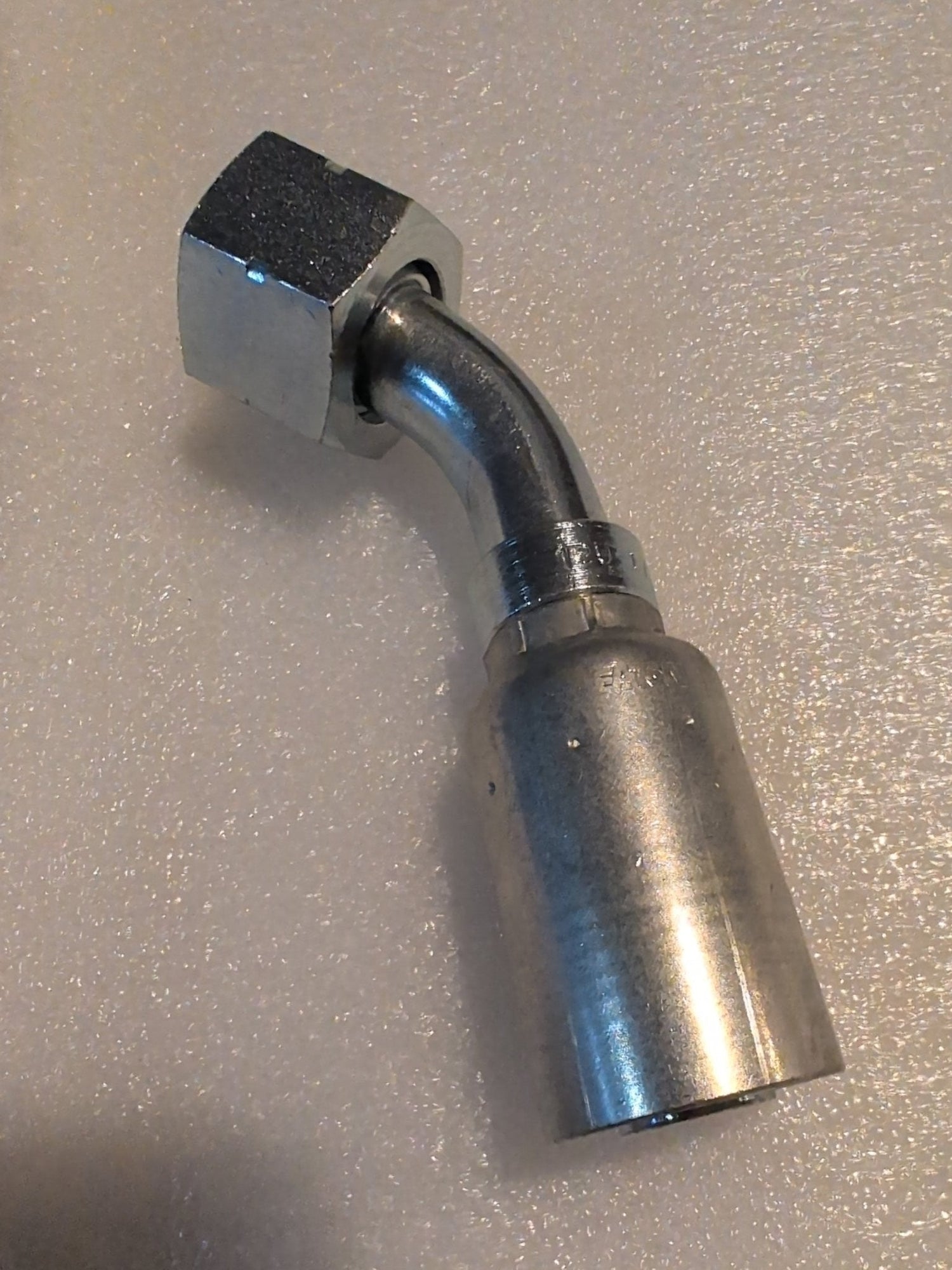 A Weatherhead 12U-L72 hydraulic hose fitting (3/4 Hose x 3/4 ORF Female, CS31-12X12) with a hexagonal nut and bent tube rests on a textured, light-colored surface.