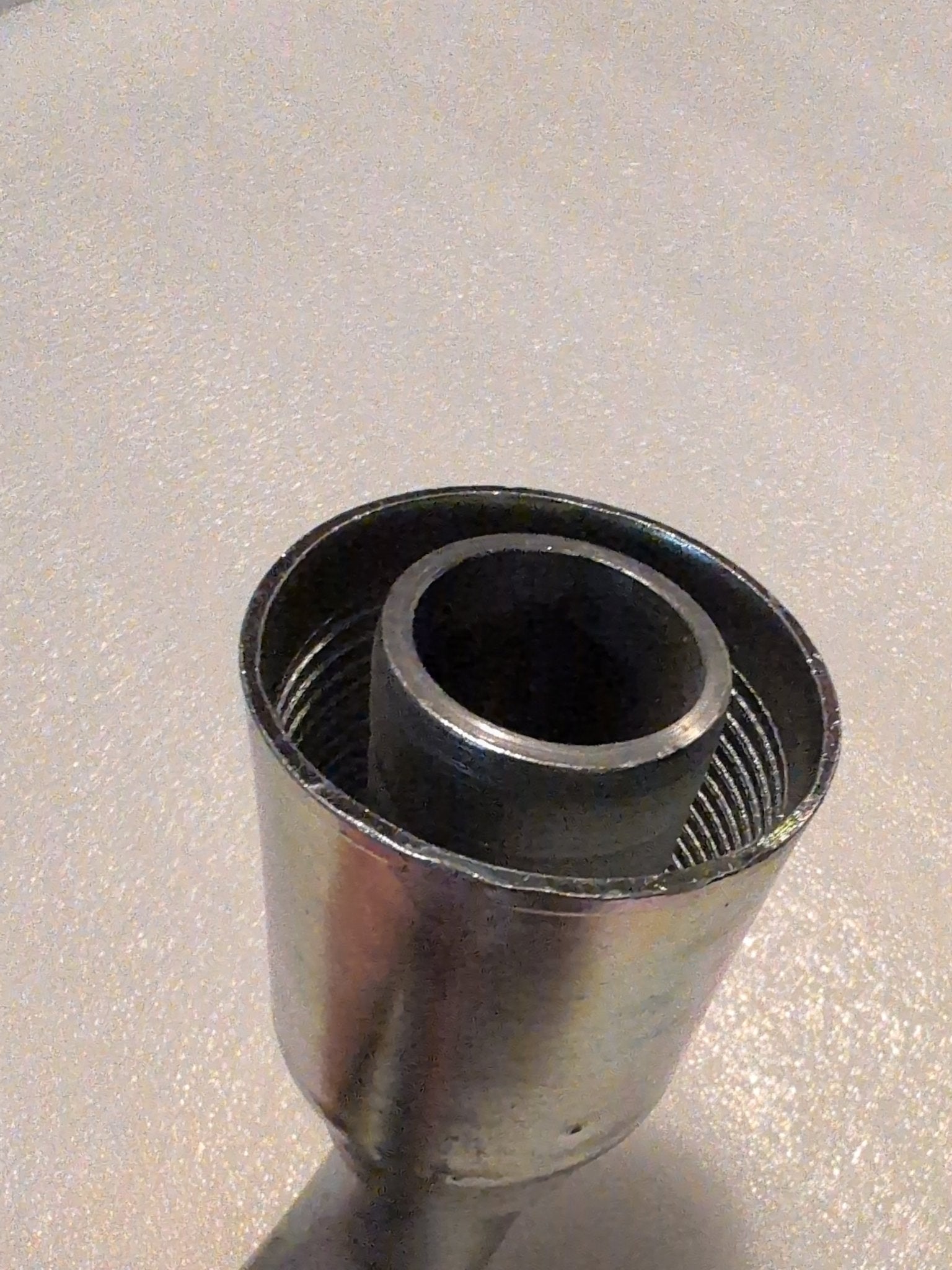 A close-up of the Weatherhead 20U-677, a 1 1/4 hose x 1 1/4 JIC female fitting (CS26-20X20), shows its metallic cylindrical body with inner threading from above, resting on a textured surface.