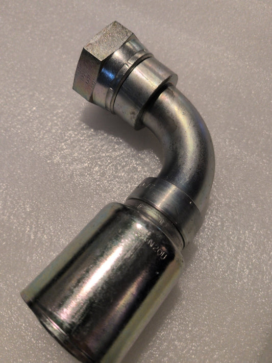 Detailed shot of a Weatherhead 20U-677 metal hydraulic hose fitting, featuring a 90-degree swivel bend with a shiny silver finish, hexagonal nut, and smooth cylindrical end, set against a textured gray surface.