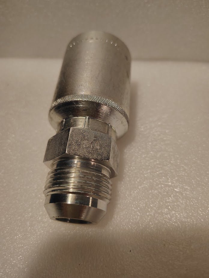 A close-up of a 43012U-514 | 3/4 Hose x 7/8 JIC Solid Straight Fitting (GW08-12x14) with a hex nut and threaded end, shown on a white textured surface.