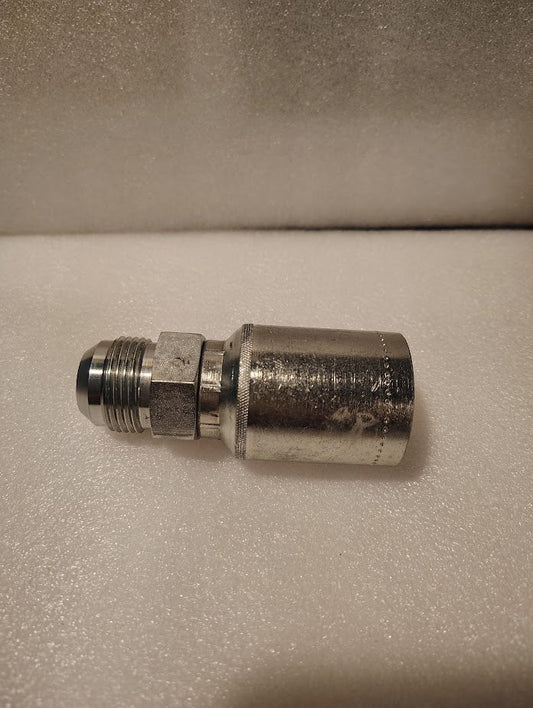 A 43012U-514 | 3/4 Hose x 7/8 JIC Solid Fitting - Straight (GW08-12x14) with a hexagonal nut and threaded connector is positioned horizontally on a white, textured surface.