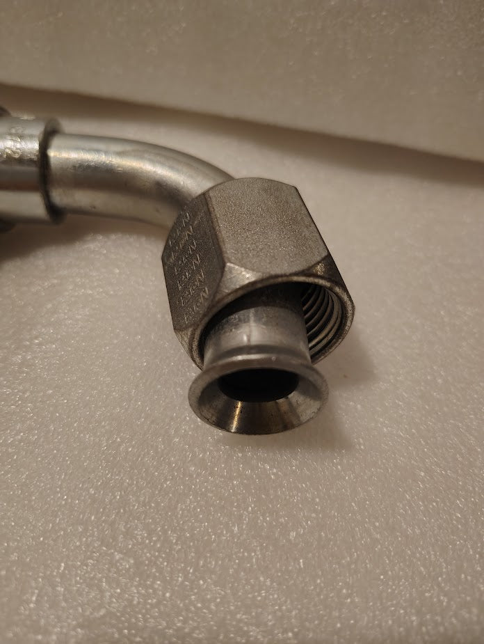 A close-up of a Weatherhead 43012U-672 (GW26-12x12) 3/4 hose x 3/4 JIC female metal fitting with a hexagonal nut and flared end, resting on a textured white surface; suitable for use with compatible hoses.
