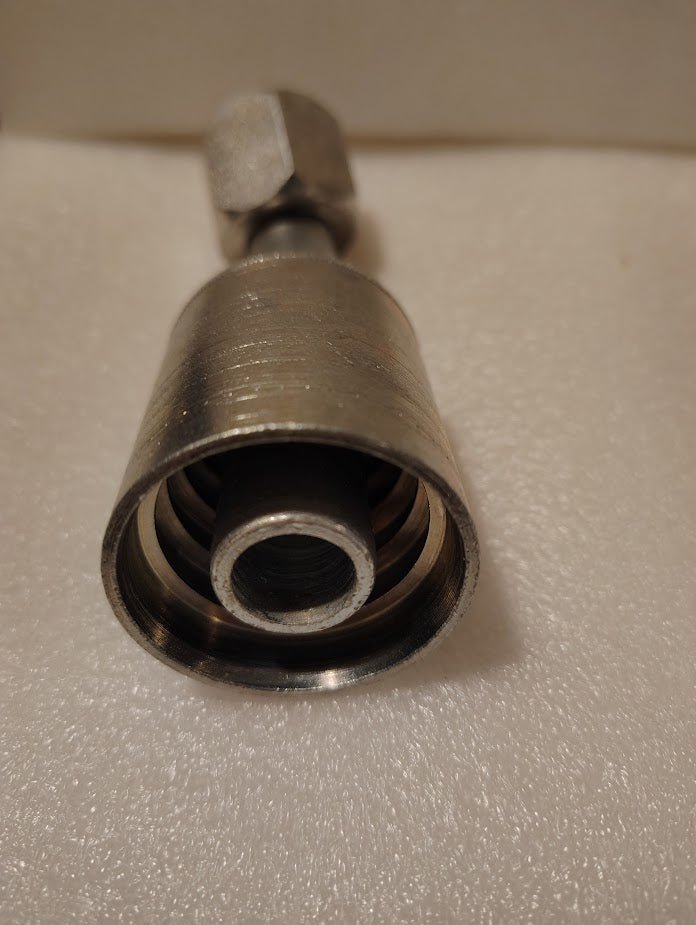 Close-up of a Weatherhead 43012U-692 (GW25-12x12) hydraulic hose fitting, 3/4 hose x 3/4 JIC female, resting on textured white surface with the open end showing inner threads.