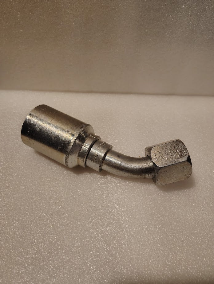 A close-up of the Weatherhead 43012U-692 3/4 Hose x 3/4 JIC Female Fitting (GW25-12x12) with a 90-degree bend, set against a textured, light-colored background. Designed for use with compatible hose styles.