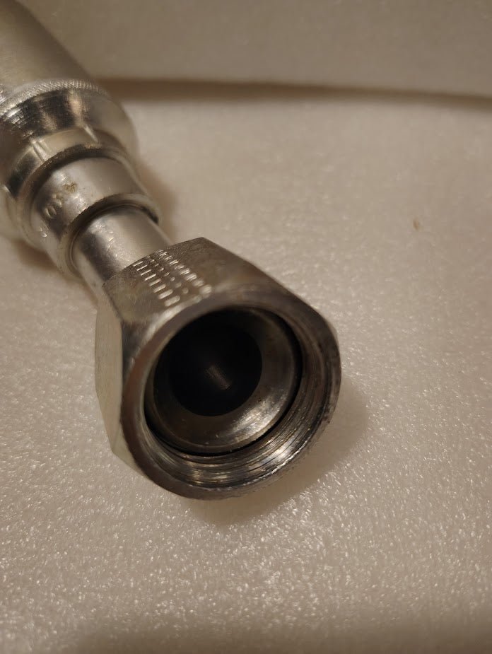 Close-up of a metal coaxial cable connector with a hexagonal nut on a white textured surface, similar to the 43012U-692 Weatherhead 3/4 Hose x 3/4 JIC Female Fitting (GW25-12x12).