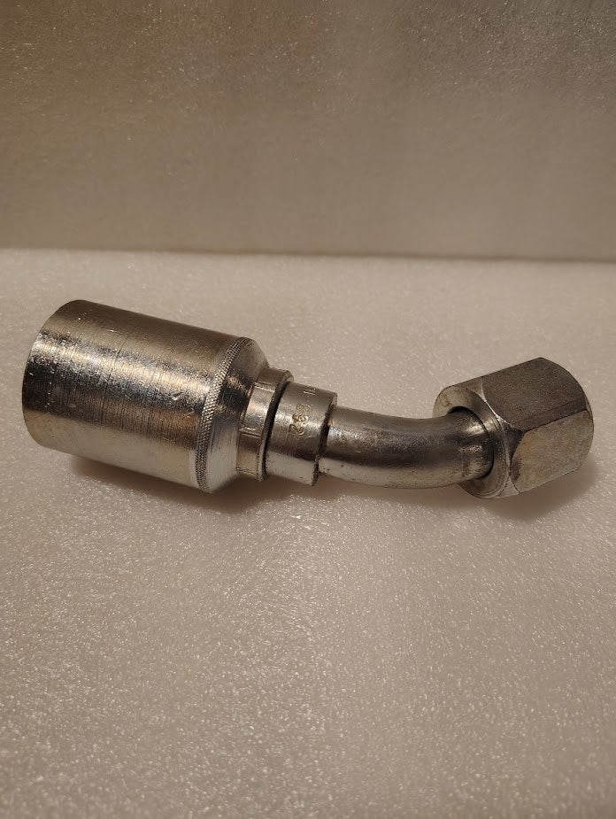 A close-up of the 43012U-692 Weatherhead 3/4 Hose x 3/4 JIC Female Fitting (GW25-12x12) with a bent tube and hexagonal nut, shown on a light textured surface.