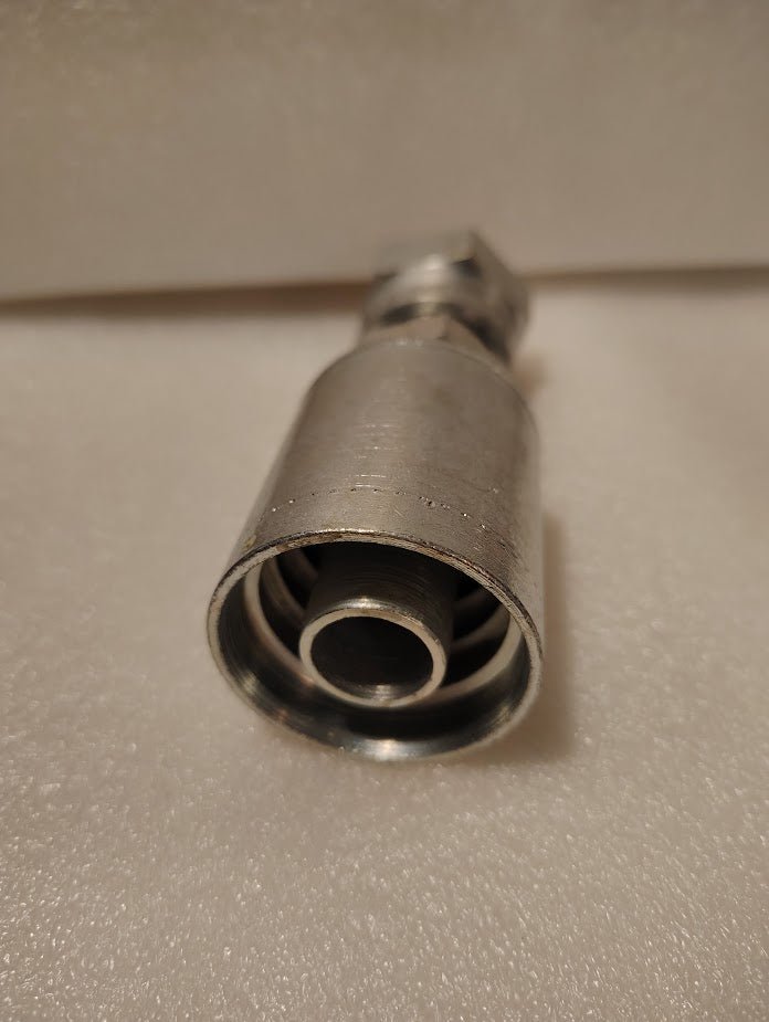 A close-up of the Weatherhead 43012U-S72, a 3/4 Hose x 3/4 ORFS Female Fitting (GW30-12x12), shows its internal threading and components on a white textured surface—ideal for compatible hoses and hydraulic hose fittings.