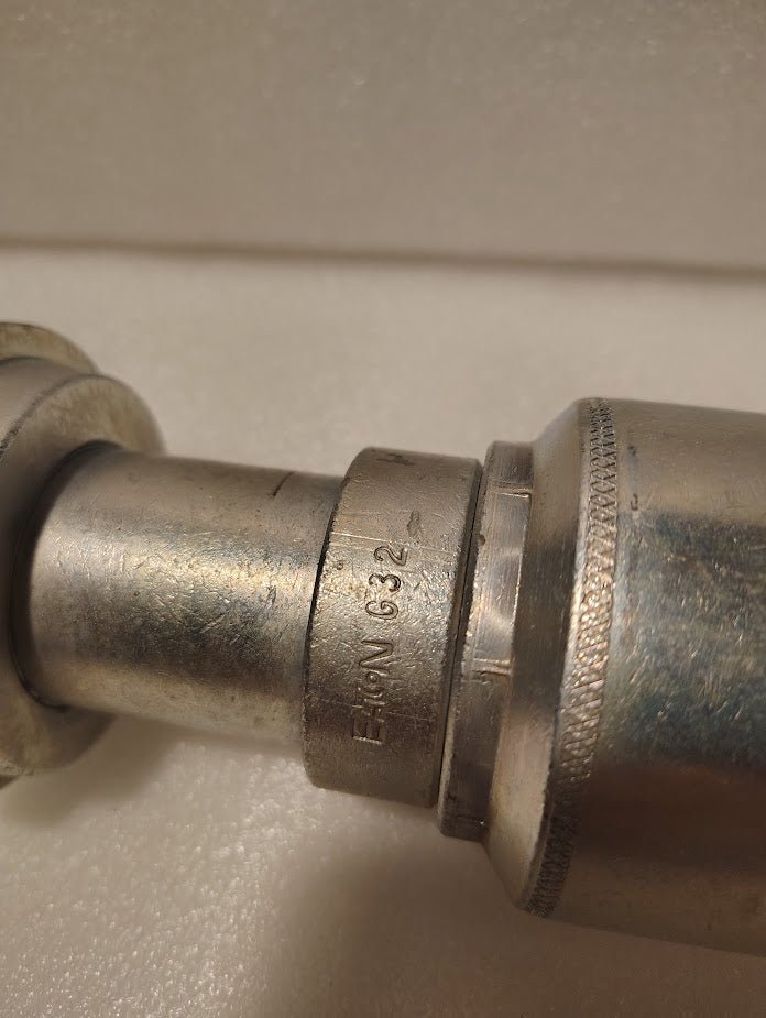A close-up of a metallic cylinder engraved EATON G32, likely the 43024U-G32 | 1 1/2 Hose x 2 Code 61 Flange Fitting - Straight (GW47-24x32), shown against a plain, light background.